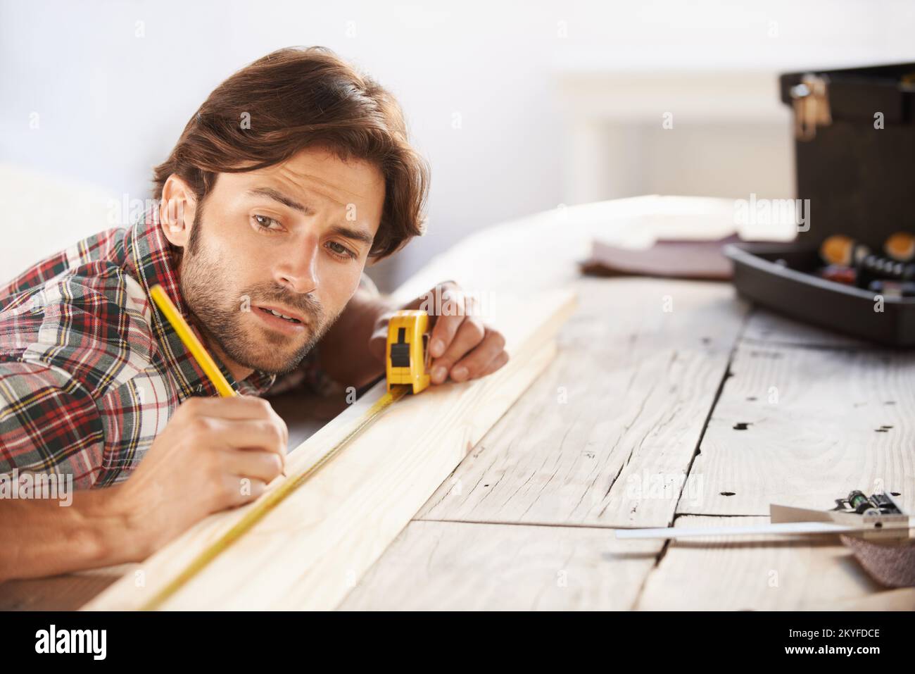 Getting the measurements right. A handsome young carpenter measuring