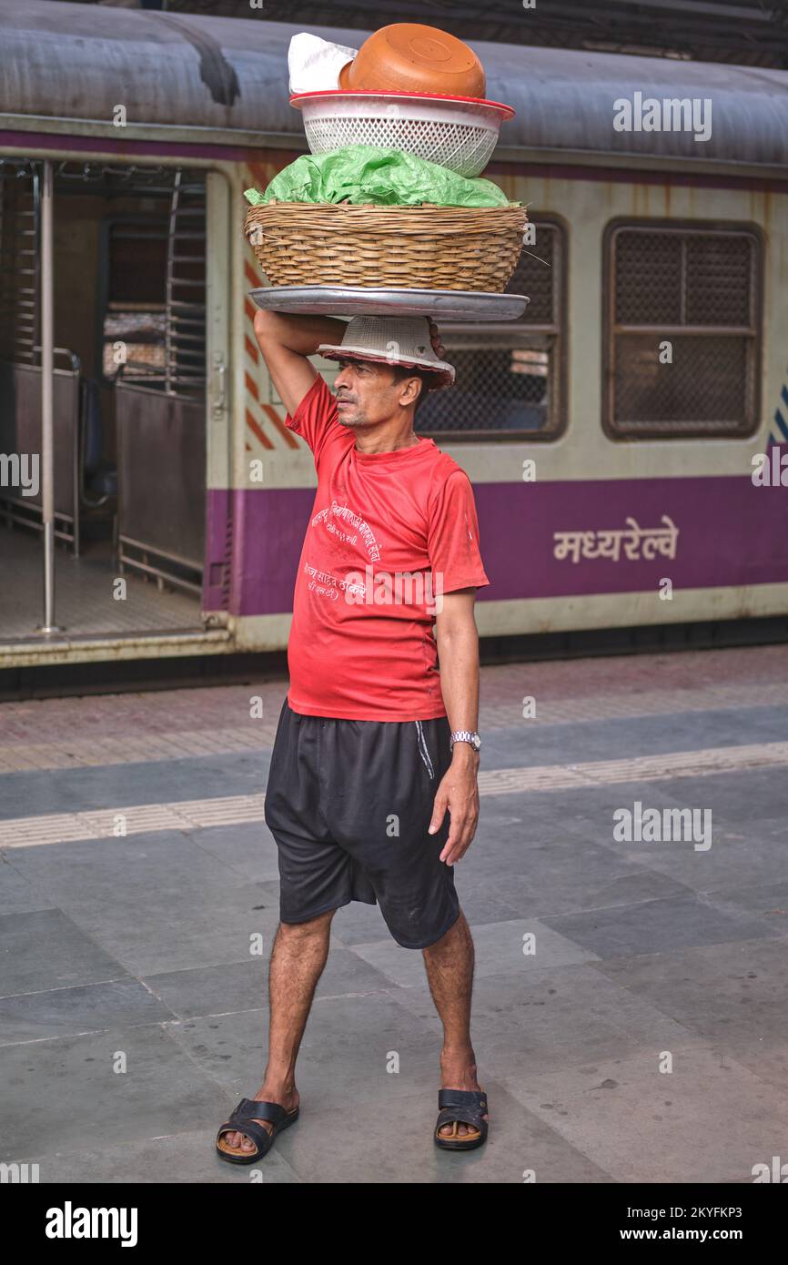 A porter at Chhatrapati Shivaji Maharaj Terminus in Mumbai, India, the city's busiest railway station, waiting for a local train to deliver his goods Stock Photo