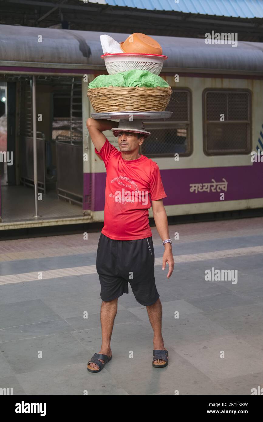 A porter at Chhatrapati Shivaji Maharaj Terminus in Mumbai, India, the city's busiest railway station, waiting for a local train to deliver his goods Stock Photo