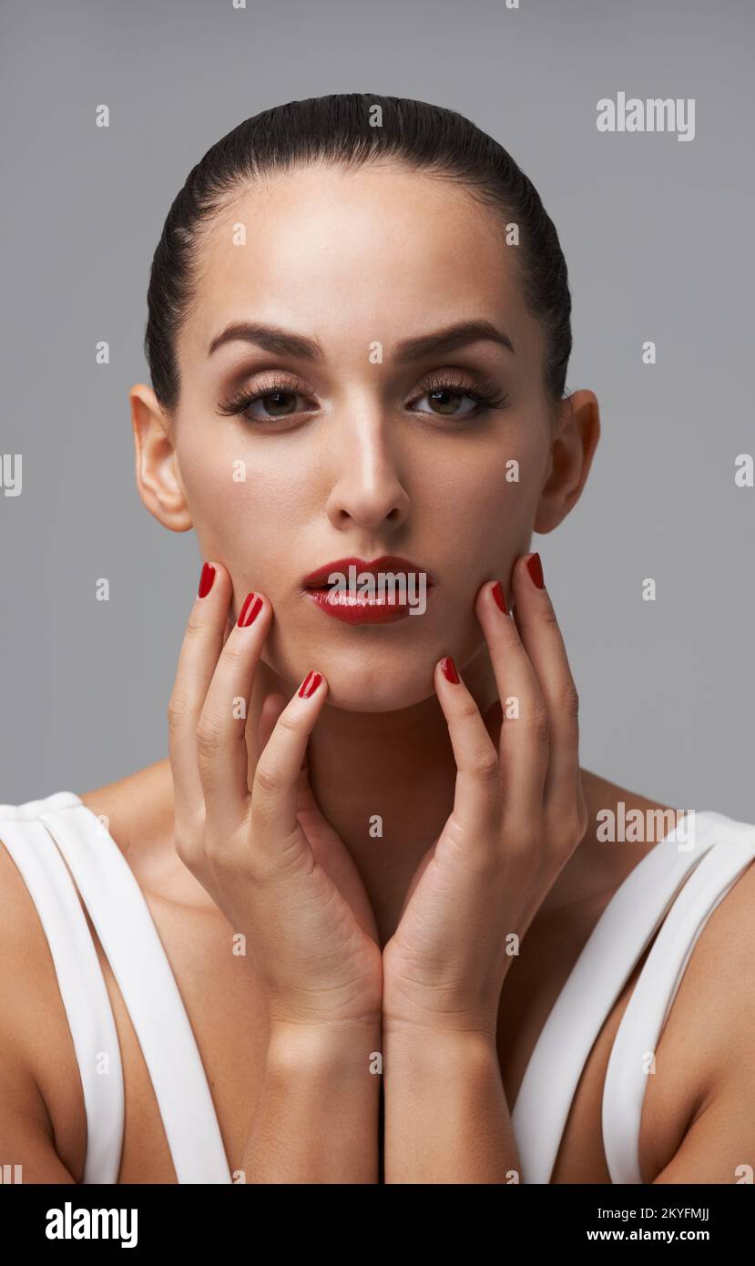 She lives life colourful. Studio portrait of a young woman wearing lipstick and nail polish. Stock Photo