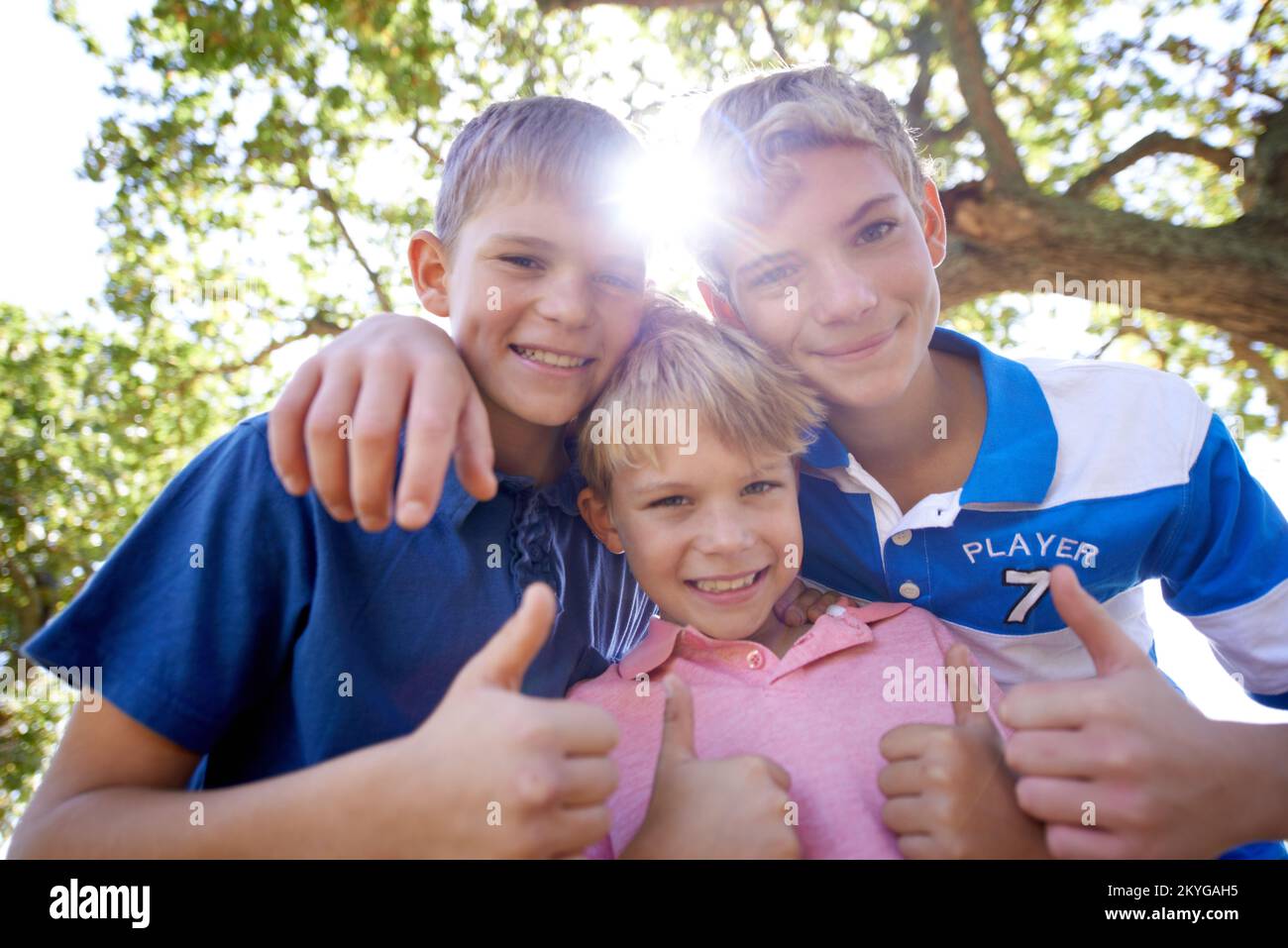 Brothers in arms. Three brothers huddling together while playing outdoors in the bright sunshine. Stock Photo