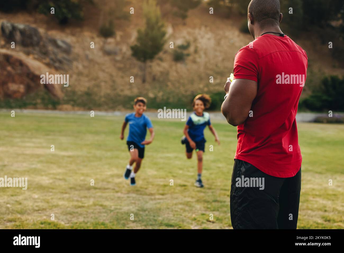 Trainer coaching an elementary school team. Sports instructor having a Rugby practice session with a group of primary school children. Student mentors Stock Photo