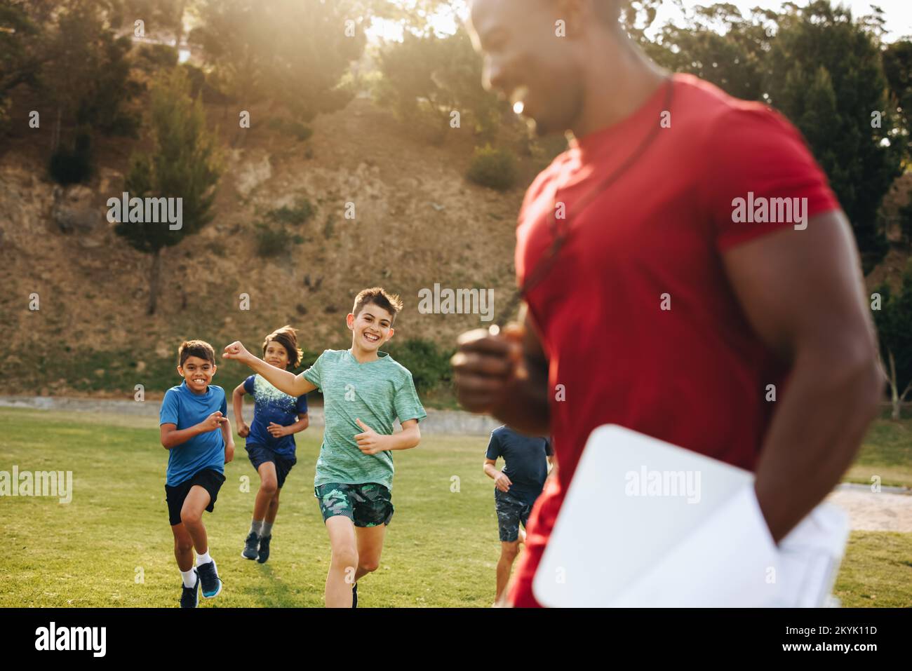 Children running on a school ground during PE. Group of elementary school kids having a physical education session with their coach. Fun sports traini Stock Photo