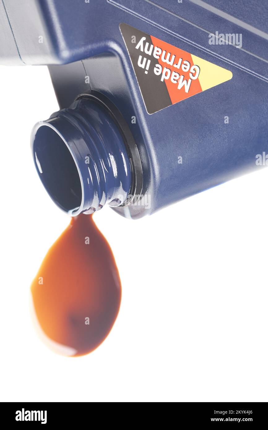open engine oil bottle with a puddle of engine oil isolated on white