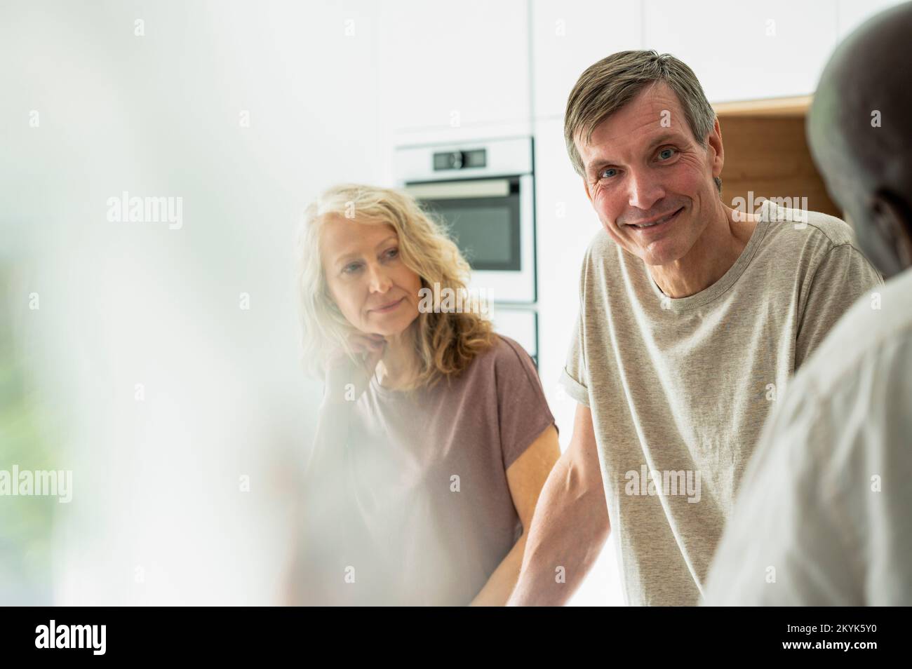 Portrait of middle-aged couple chatting with friends in kitchen Stock Photo