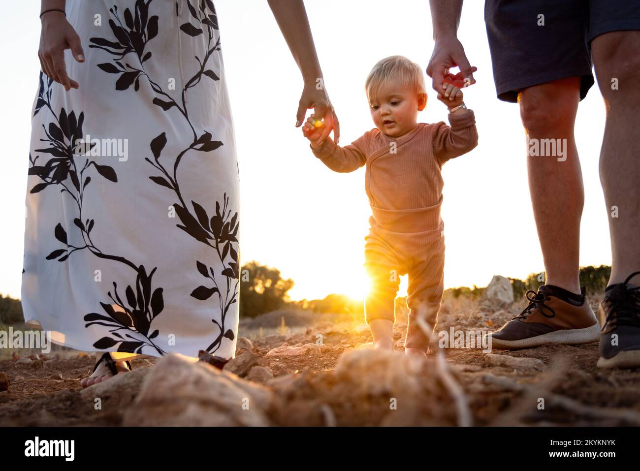 Little girl learning to walk with the help of her parents Stock Photo