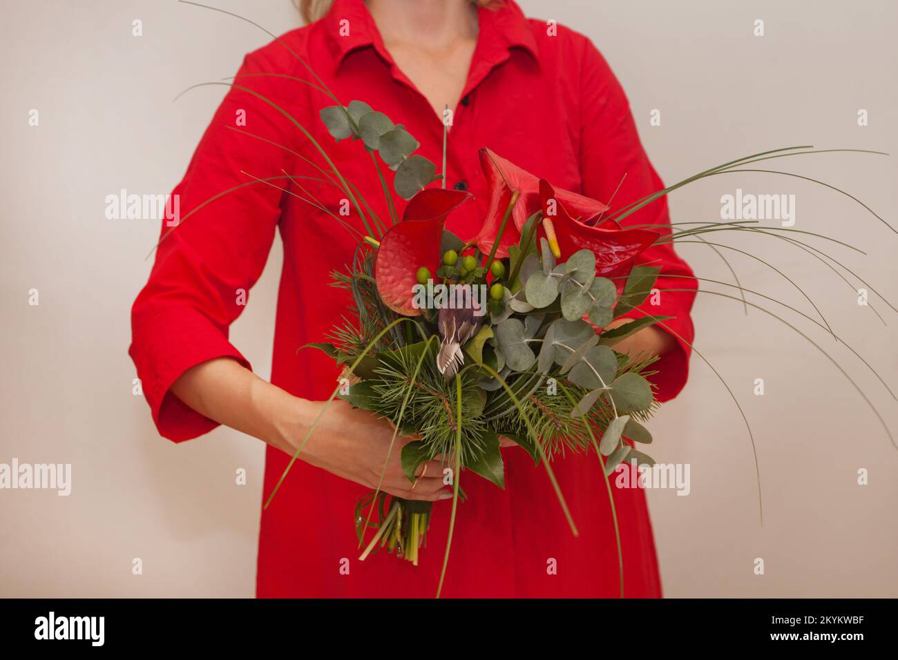 red christmas bouquet. womans hands with calla flower. decoration with bird, brunia and fir. holiday Stock Photo