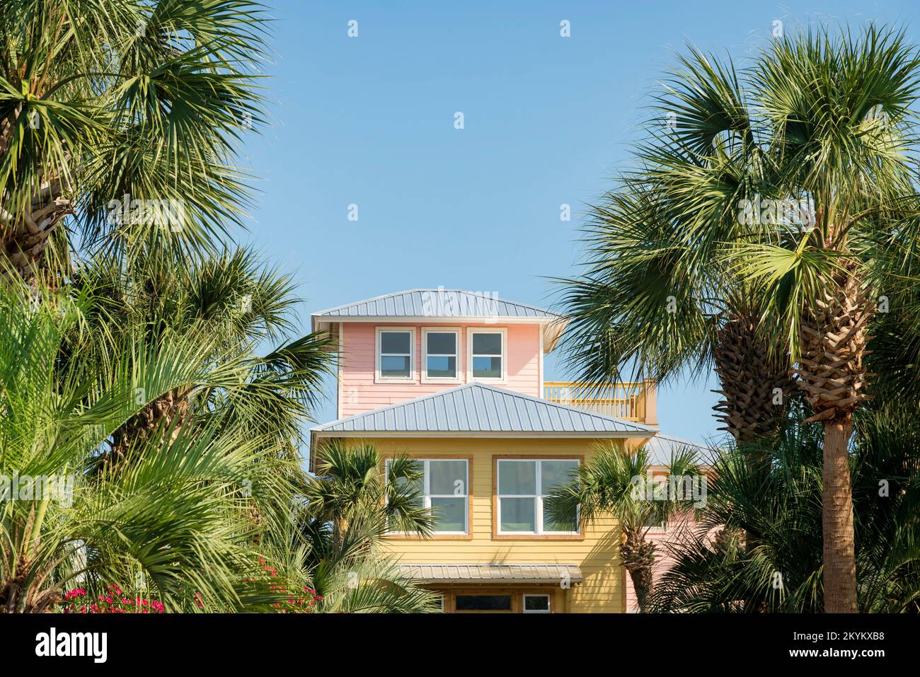 Threestorey house with pastel pink and yellow painted wood siding in