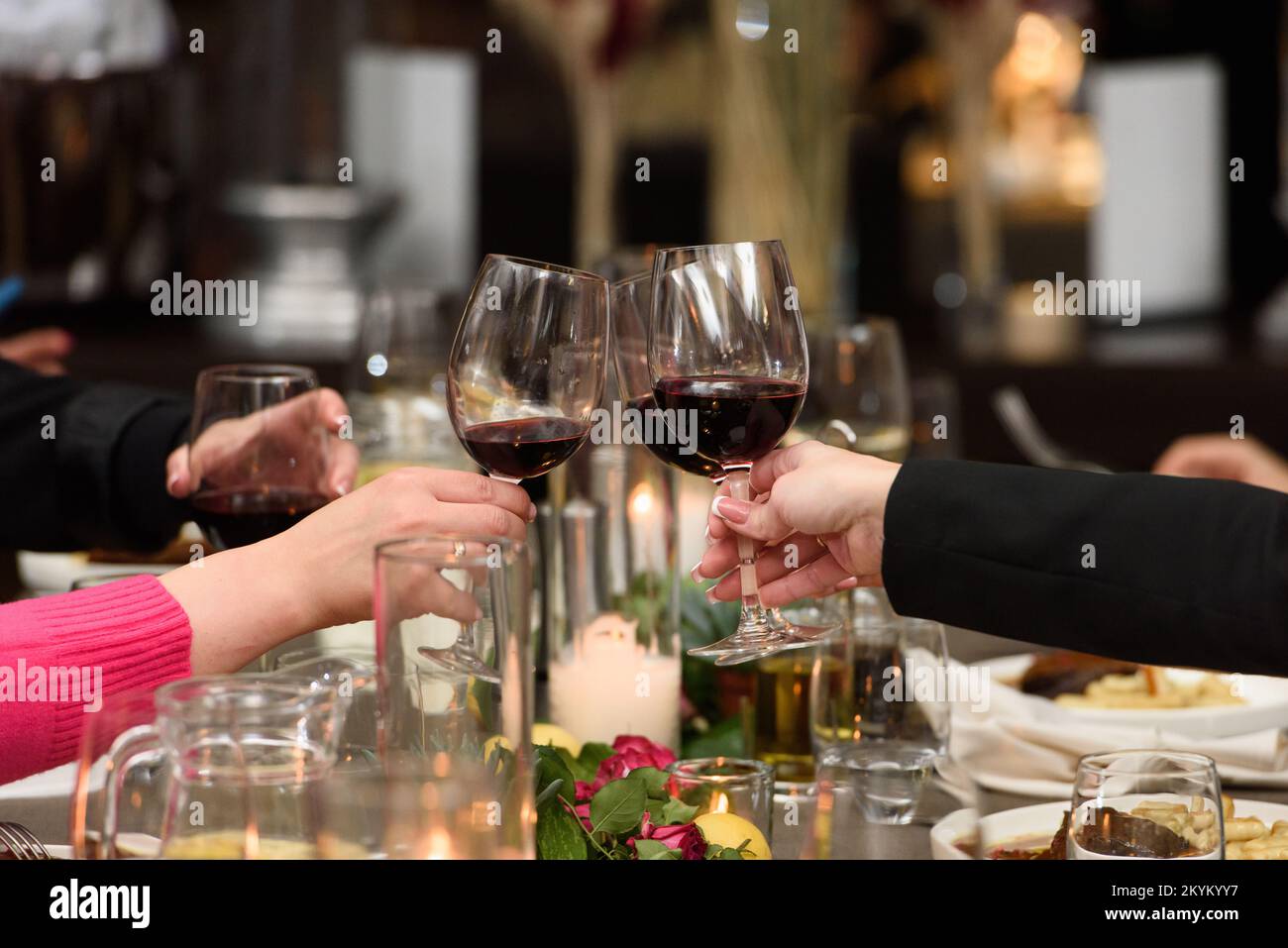 People hold in hands glasses with red wine. wedding party. friends toasting with a wine above table Stock Photo