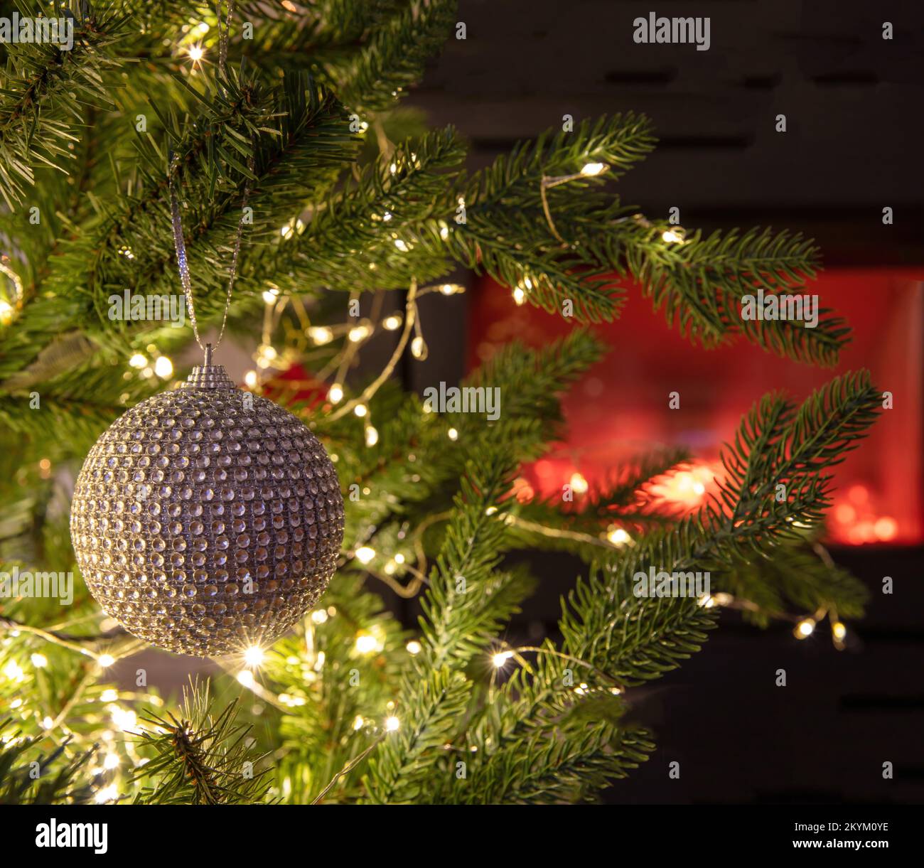Christmas background. Xmas tree decoration bauble and lights close up view, burning fireplace, copy space. Stock Photo