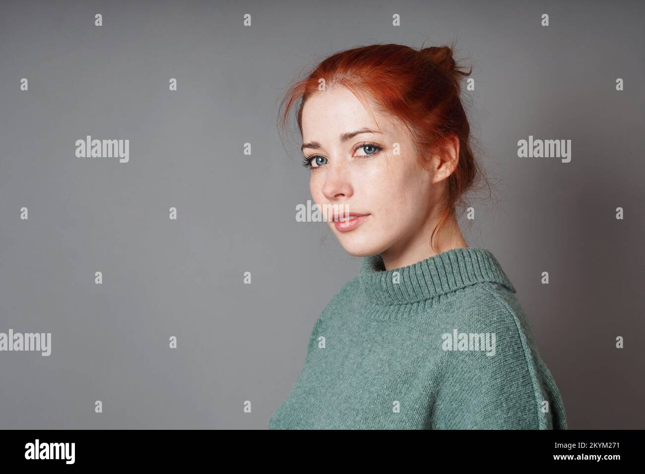 young woman with red hair bun and roll neck pullover Stock Photo