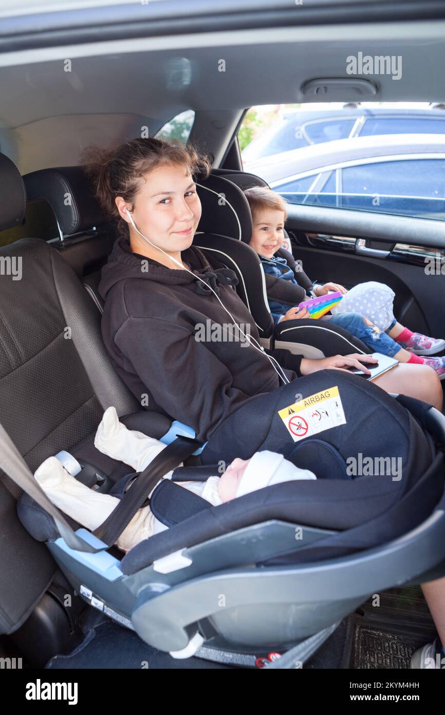 Children of different ages sit in the back seat of a car, Caucasian