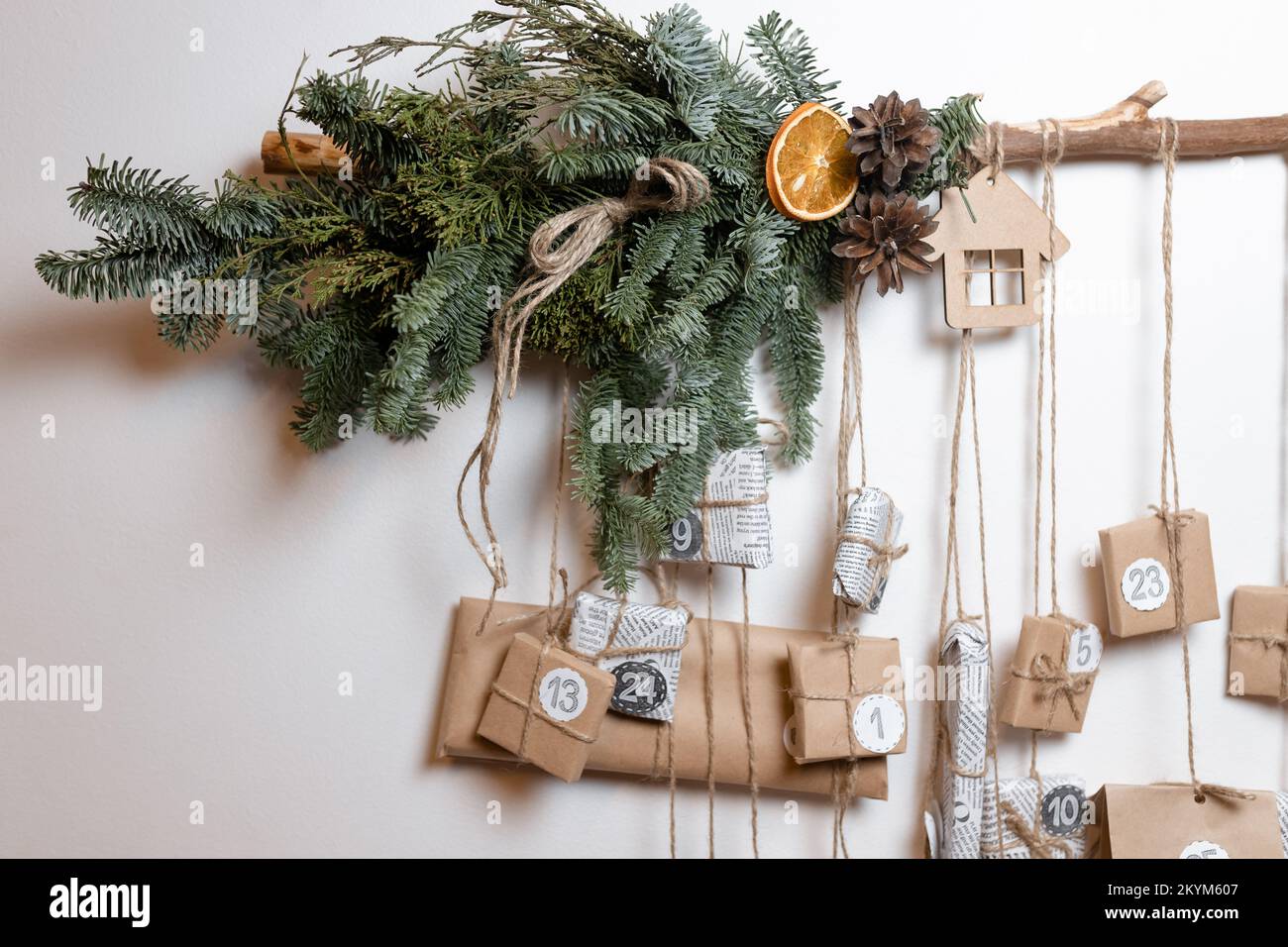 A Christmas advent calendar with gifts and decorations hangs on a white