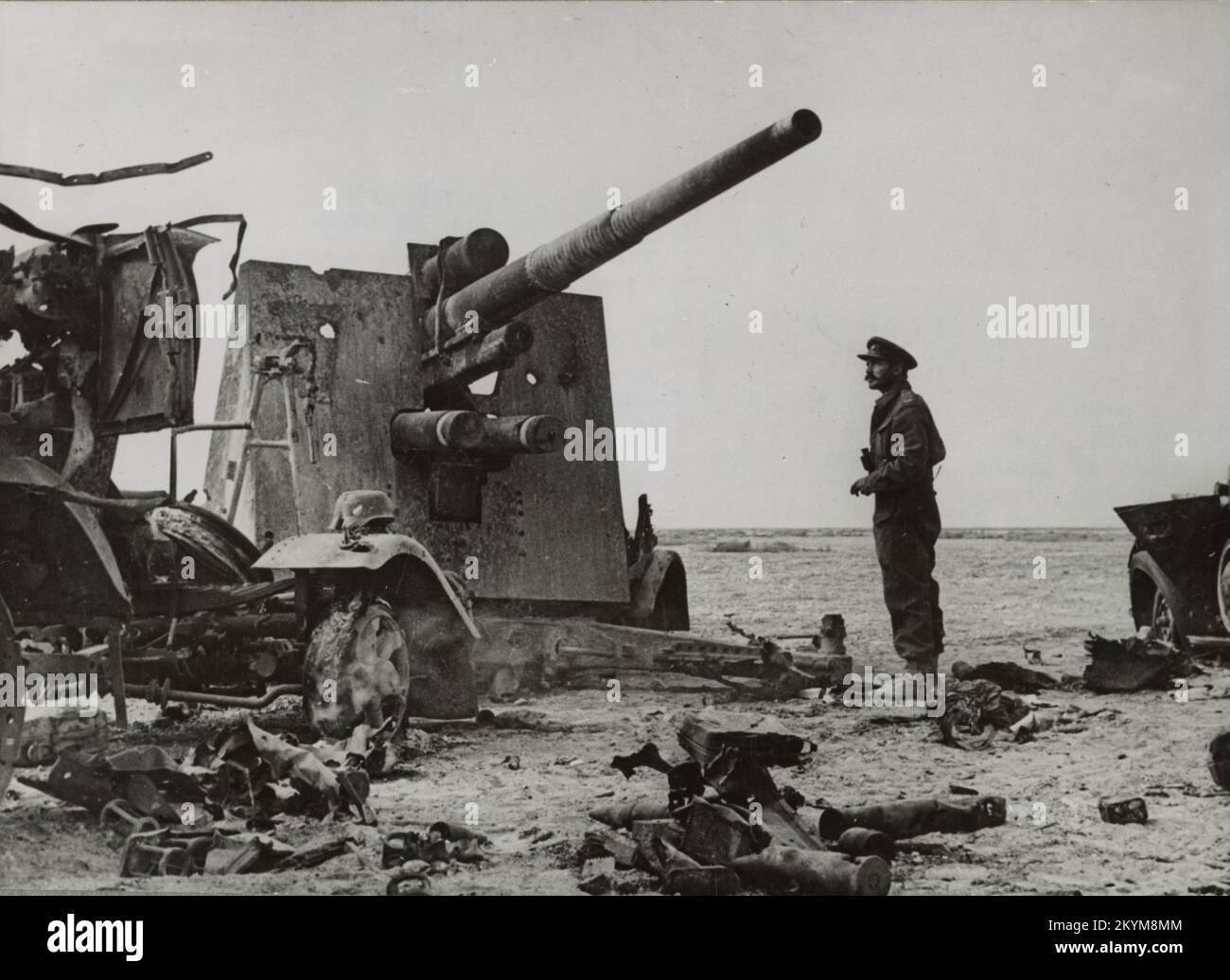 Vintage photo circa November 1941 of a British army officer examining the wreckage of a German 88mm artillery gun destroyed at Bir el Gubi in North Africa during World War Two Stock Photo