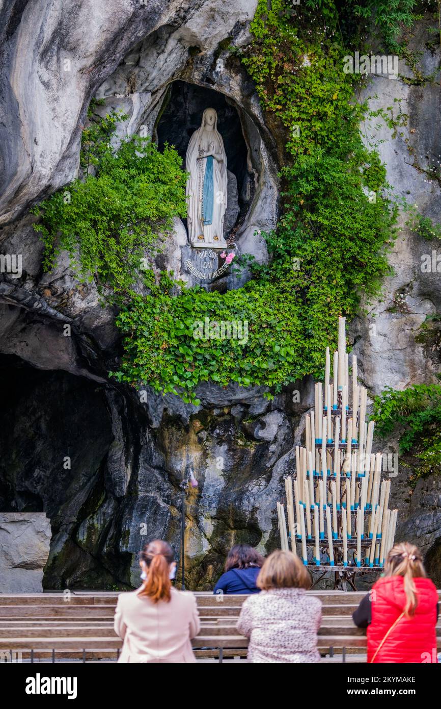 Pilgrims praying in front of the Grotto of Lourdes with Bernadette