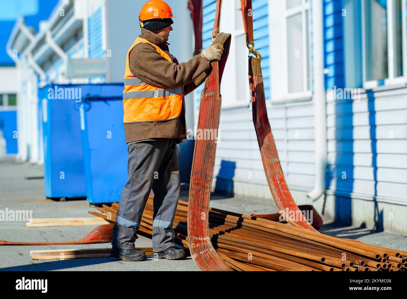 Slinger stacks thin metal pipes in stack on construction site. Closeup