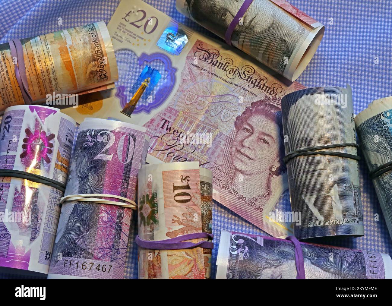 Rolls of British Scottish notes held by elastic bands, surrounding a Bank Of England 20 pound note. Stock Photo