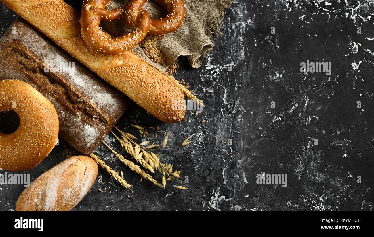 Fresh baked bread assortment on black board background. Top view Stock Photo