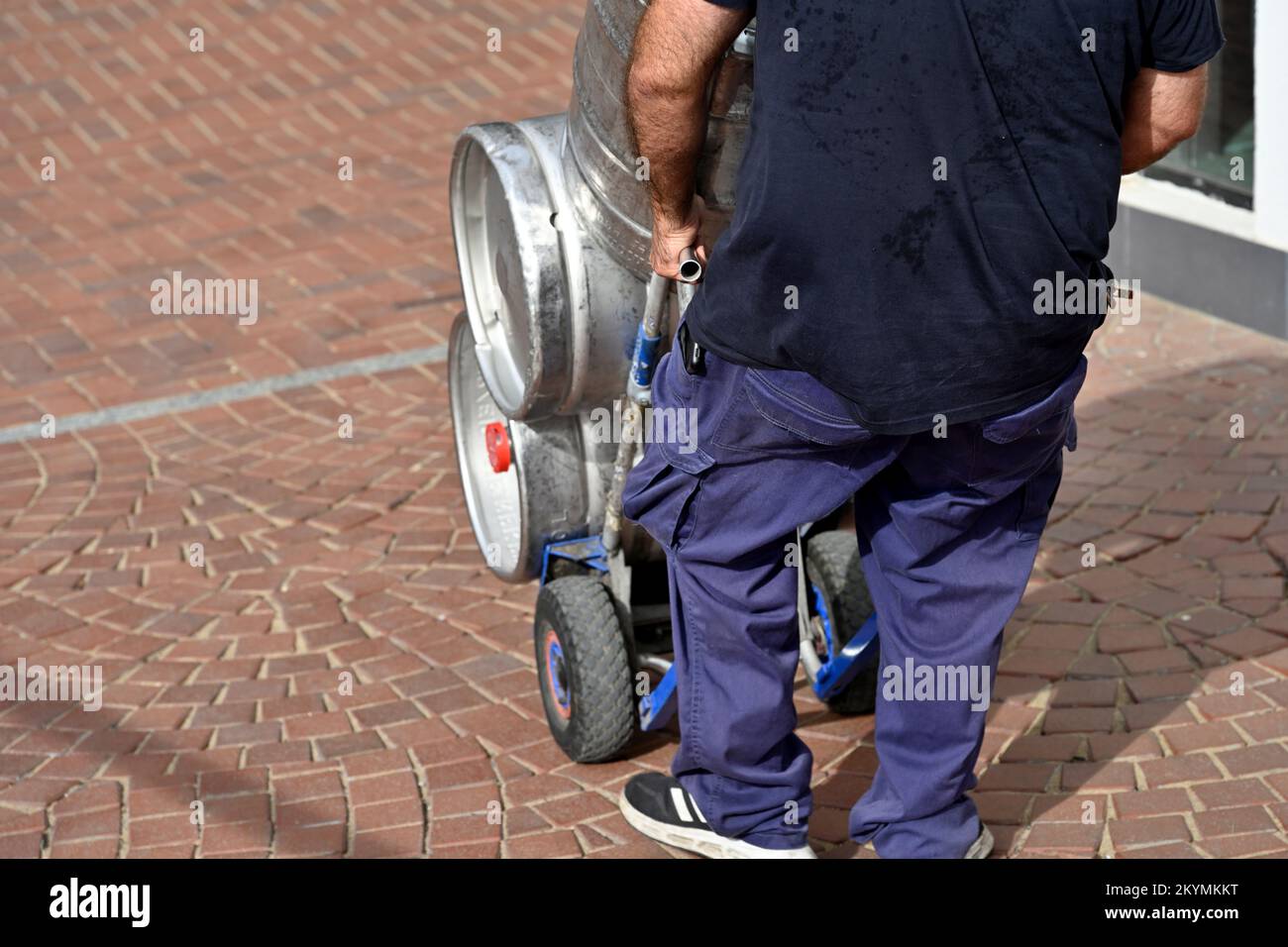 Man moving beer kegs on trolley Stock Photo