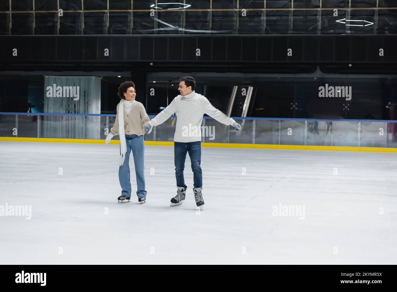 Positive interracial couple ice skating during date on rink Stock Photo ...