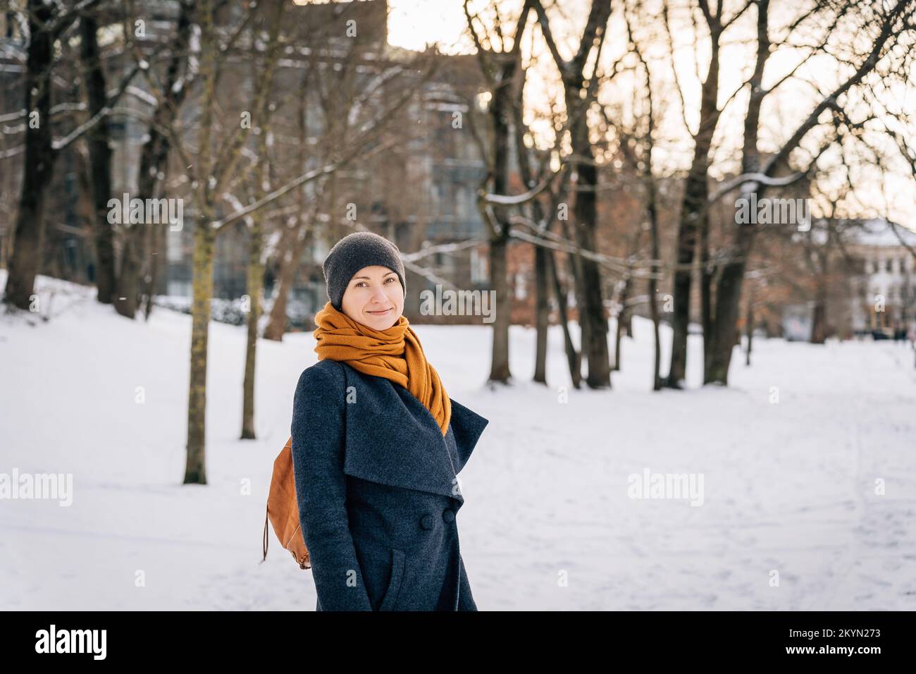 A woman in warm winter clothes looks into the camera and smiles in winter Stock Photo