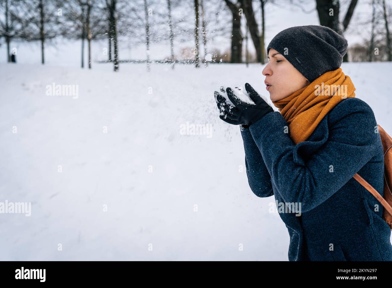 A young woman blows on the snow in her palms Stock Photo