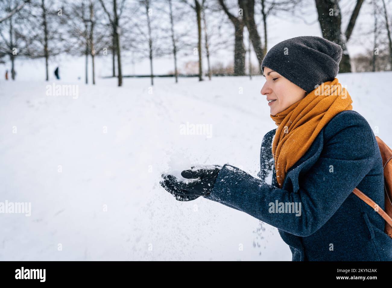 A woman in warm clothes throws snow with her hands Stock Photo