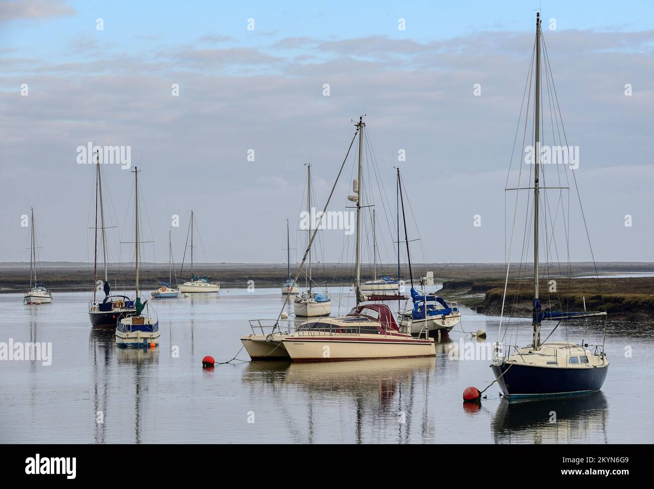 Boats reflected in the calm waters of the harbour at Wells-next-the-Sea in Norfolk on a still December day Stock Photo
