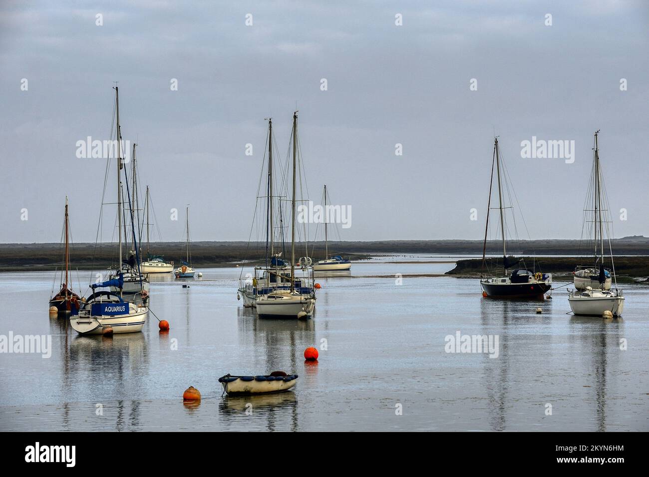 Boats reflected in the calm waters of the harbour at Wells-next-the-Sea in Norfolk on a still December day Stock Photo