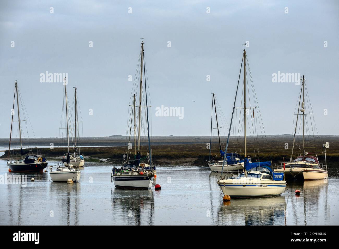 Boats reflected in the calm waters of the harbour at Wells-next-the-Sea in Norfolk on a still December day Stock Photo