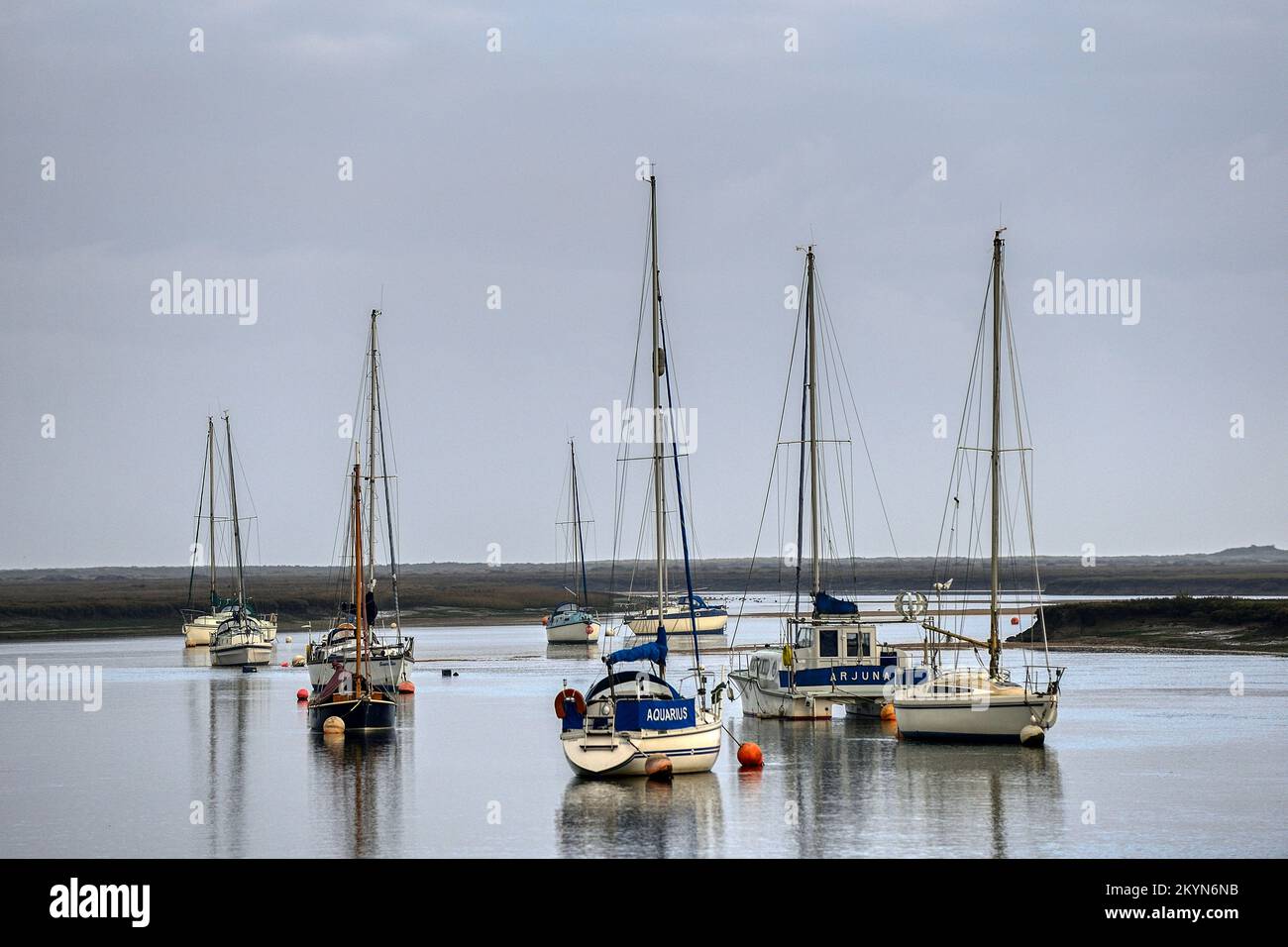 Boats reflected in the calm waters of the harbour at Wells-next-the-Sea in Norfolk on a still December day Stock Photo