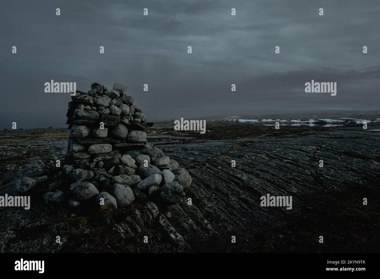 dark moody northern landscape, cairn stack of stones on top of a mountain at dusk Stock Photo