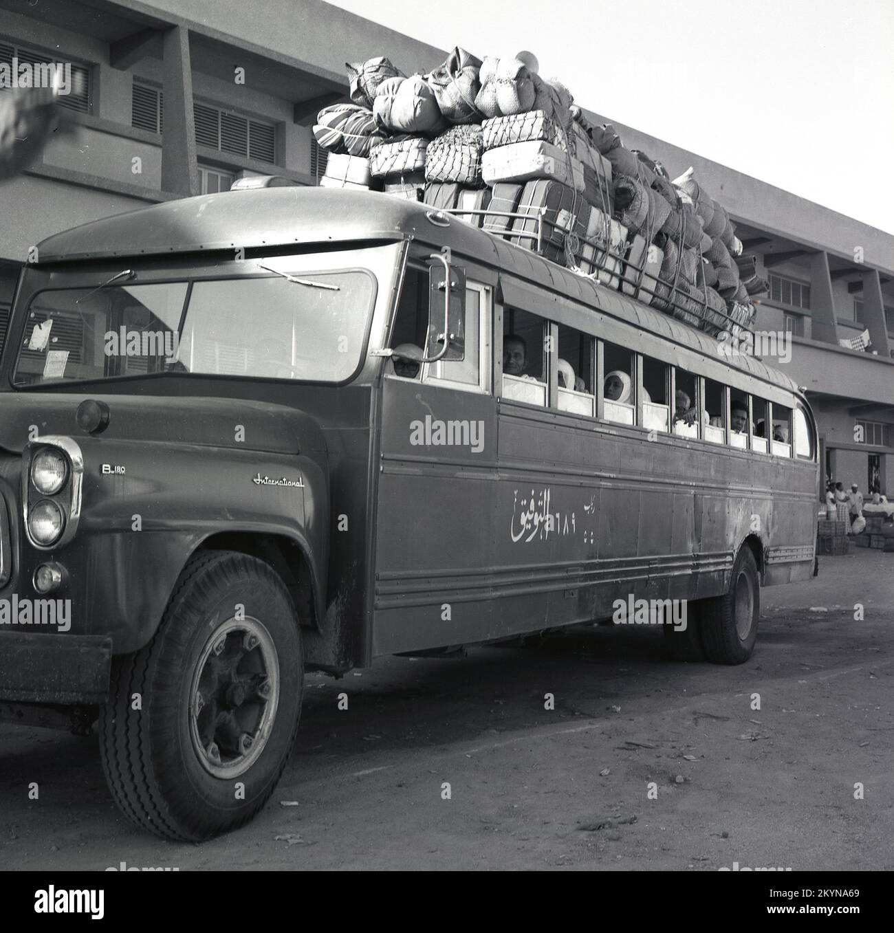 1960s, historical, parked outside an imported American International Harvester B series bus, with passengers sitting inside and a large amounf of luggage and cargo loaded on the roof, tied down with string, Riyadh, Saudi Arabia. Stock Photo