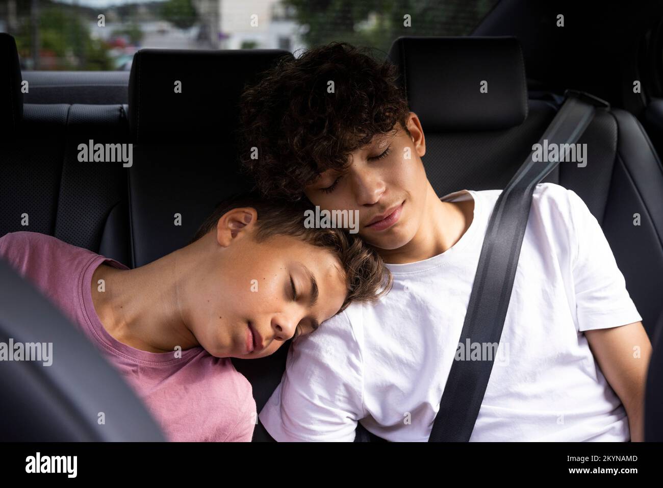 Tired brothers leaning on each other while resting in car Stock Photo