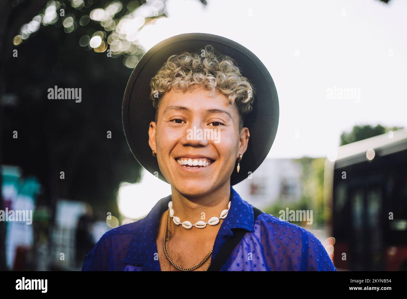 Portrait of happy young man with curly hair wearing hat Stock Photo