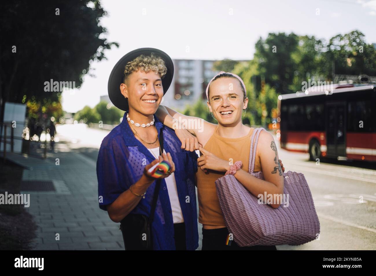 Portrait of happy non-binary person standing by young man wearing hat Stock Photo