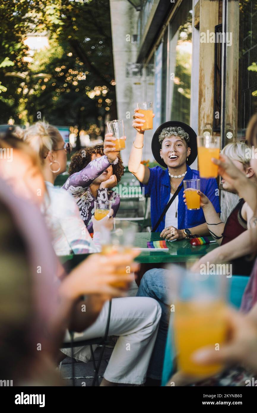 Happy young man enjoying drink while sitting with friends Stock Photo
