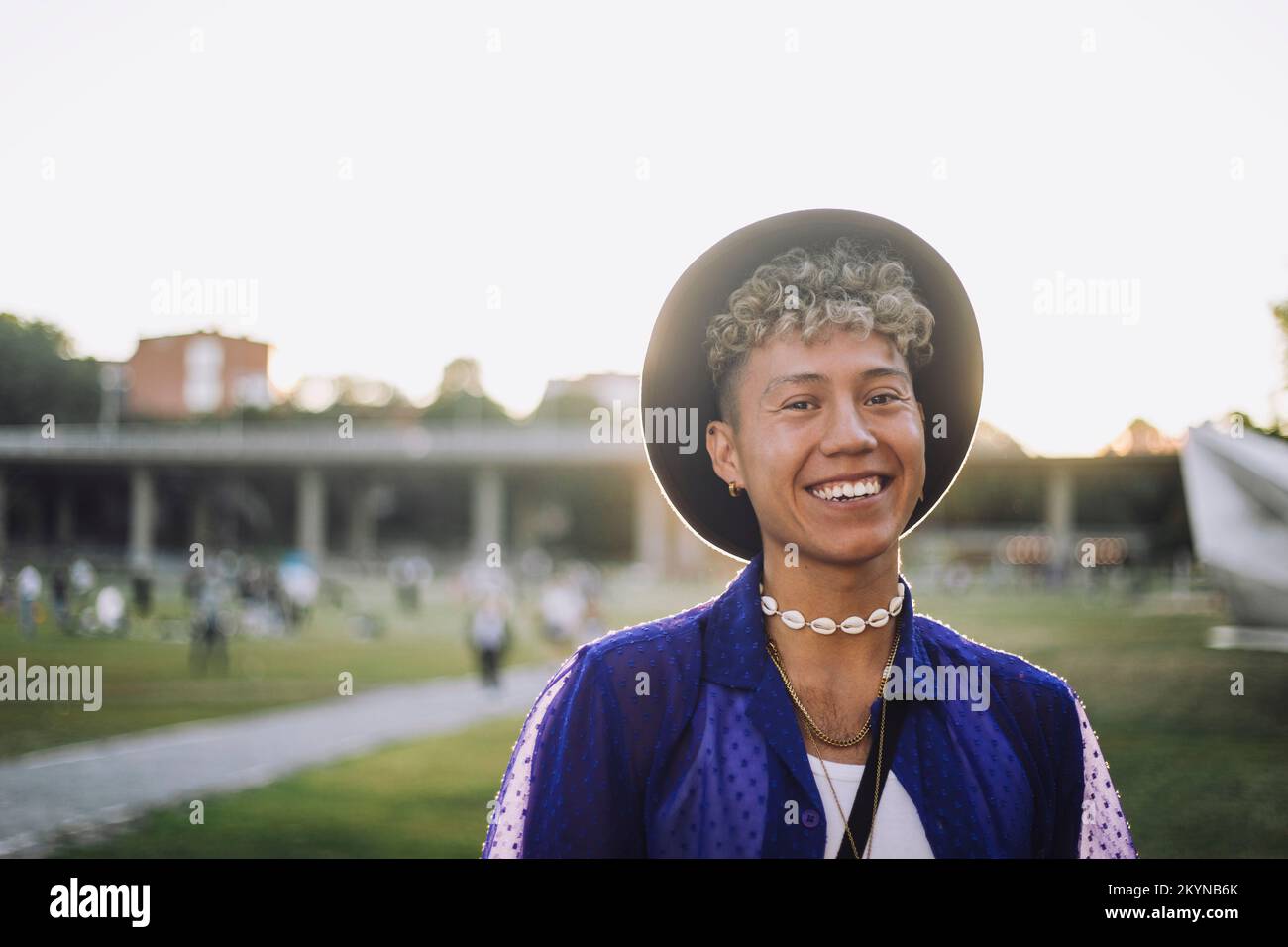 Portrait of happy young man with curly hair wearing hat at park Stock Photo