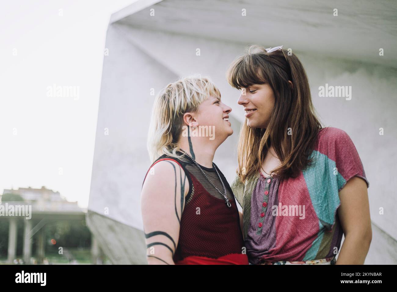 Smiling young couple looking at each other against wall Stock Photo