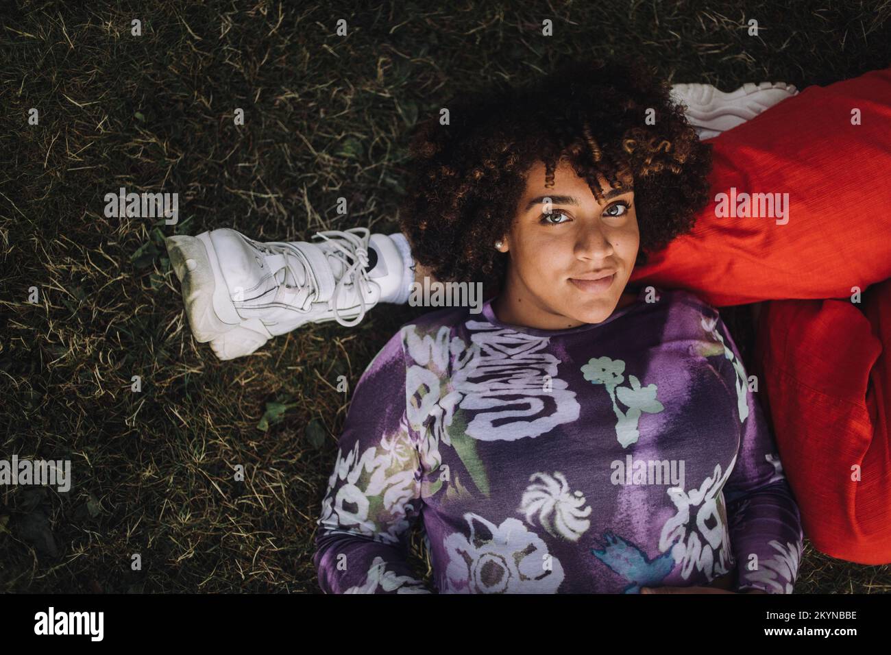 Portrait of smiling transgender woman lying on non-binary friend's leg Stock Photo
