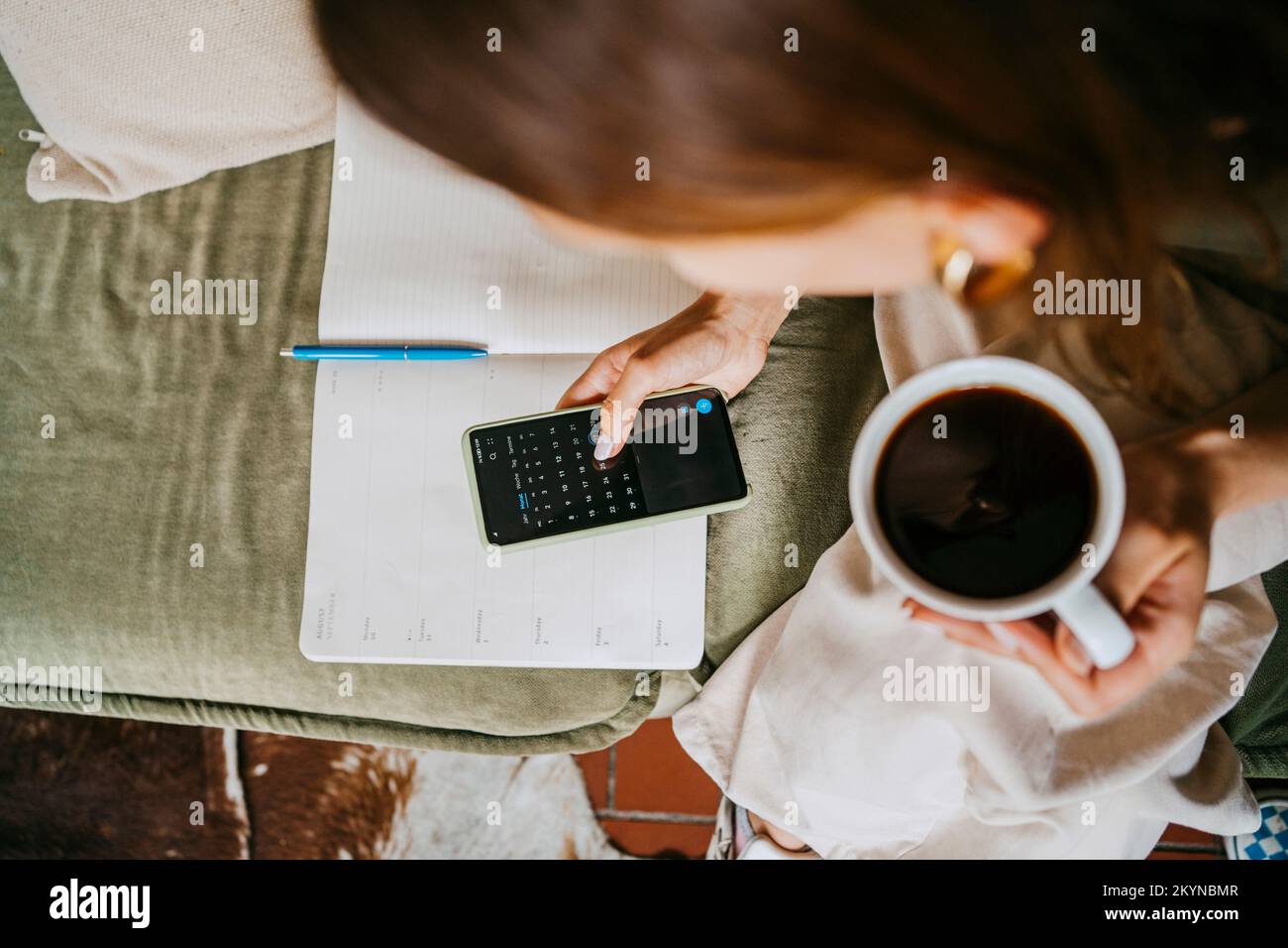 Entrepreneur using calendar on smart phone holding coffee cup at studio Stock Photo