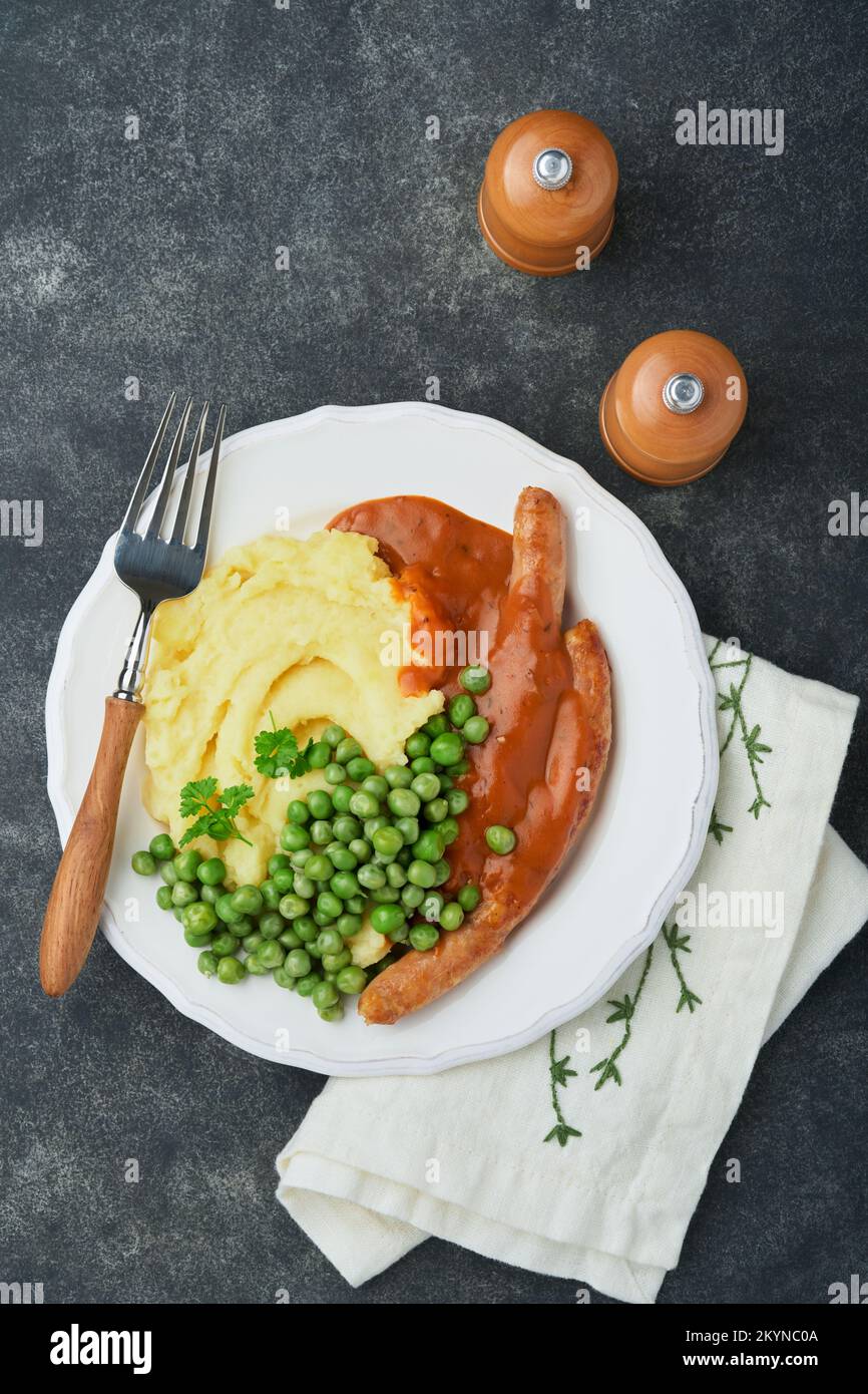 Bangers and mash. Grilled sausages with mash potato and green pea on