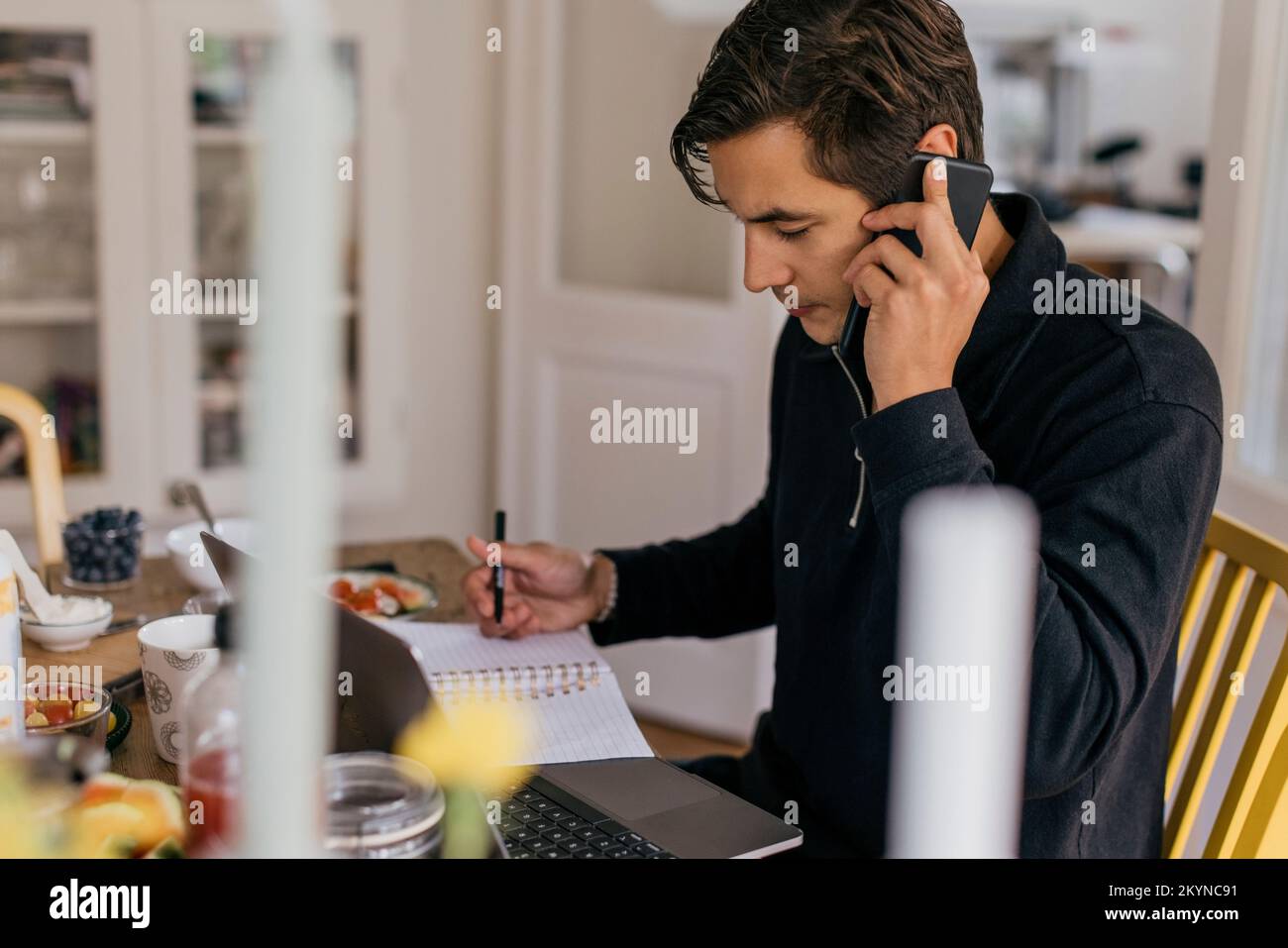 Young businessman talking on smart phone while working from home Stock Photo