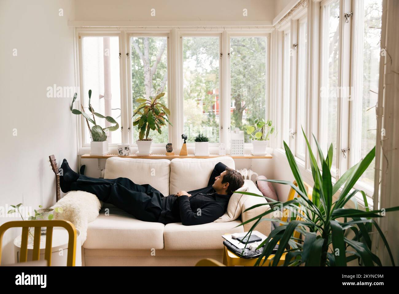 Side view of man sleeping on sofa in living room at home Stock Photo