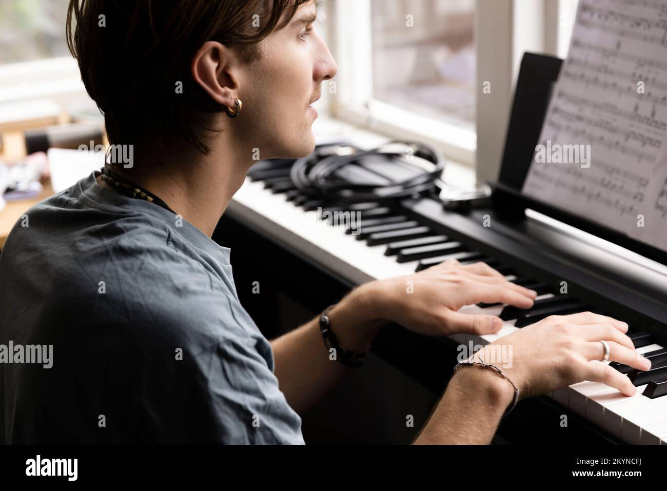 Concentrated young man practicing piano at home Stock Photo