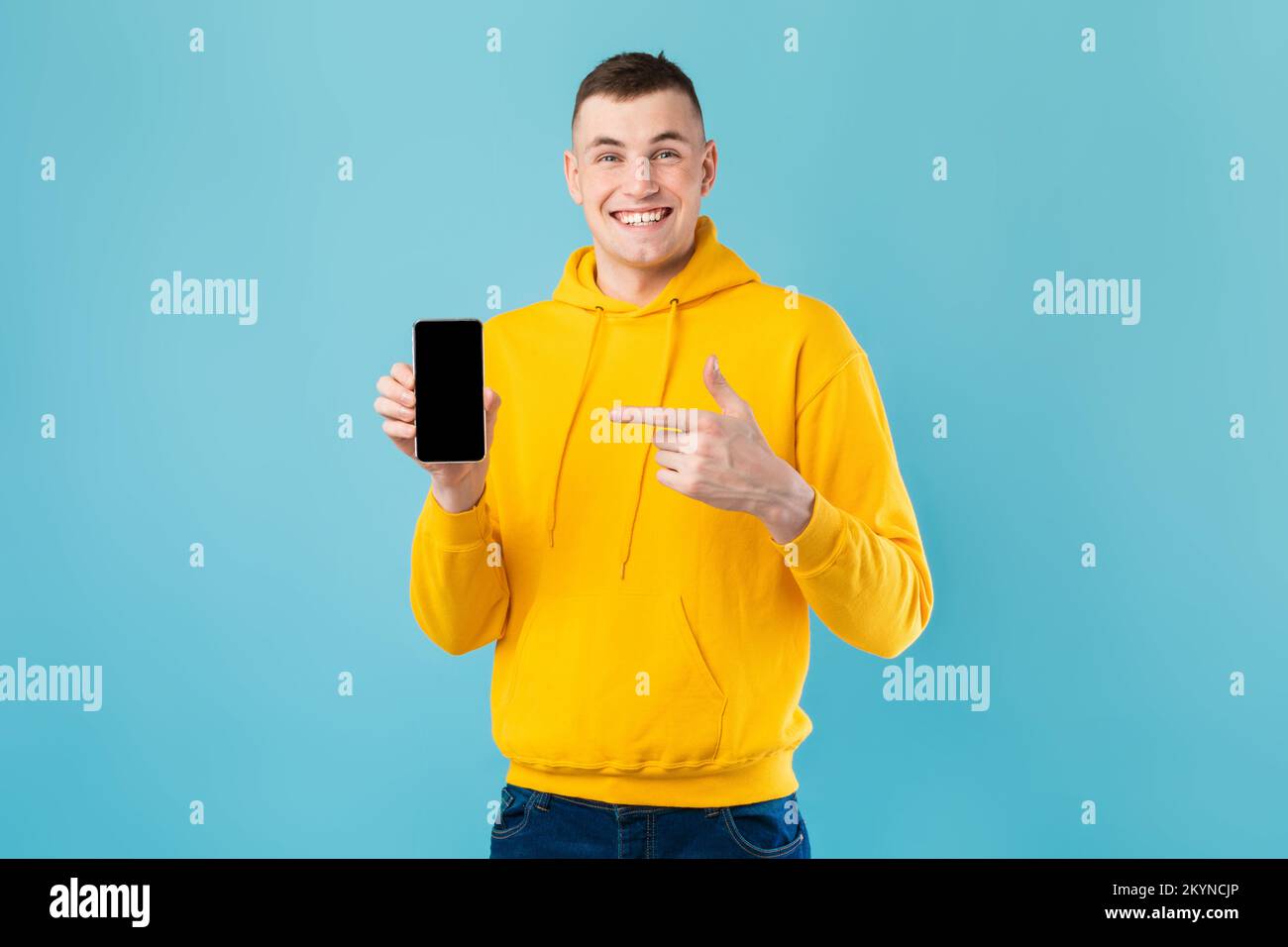 Excited handsome caucasian guy demonstrating smartphone with black blank screen and pointing on it, mockup Stock Photo