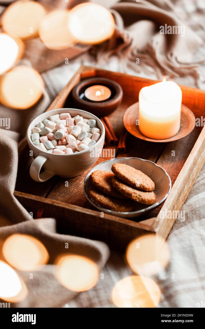 warm cozy bedroom winter or autumn interior with cup of hot chocolate on tray, candles christmas lights Stock Photo