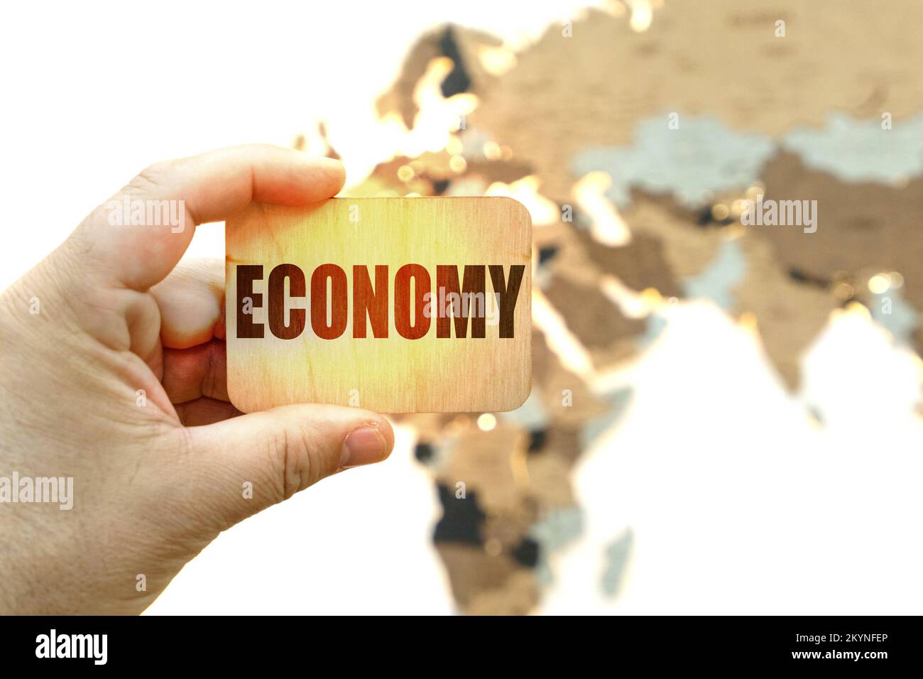 Business concept. Against the background of the world map, a man holds a sign with the inscription - ECONOMY Stock Photo