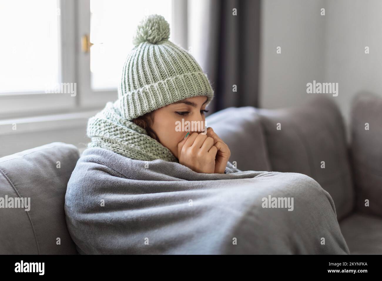 Heating Problems. Closeup Shot Of Young Woman Freezing At Home Stock Photo
