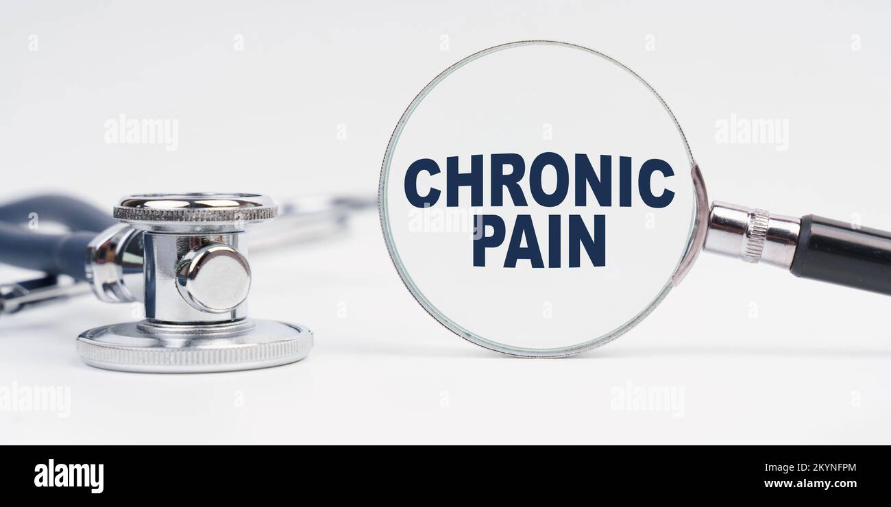 Medicine and health concept. There is a stethoscope on the table, a magnifying glass with the inscription - CHRONIC PAIN Stock Photo